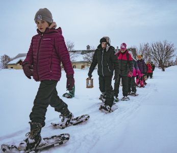 Lumikenkäilijöiden jono, kaikilla on lyhdyt kädessä.