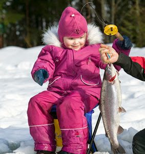 Pikkutyttö saa pilkkiongella kirjolohen.