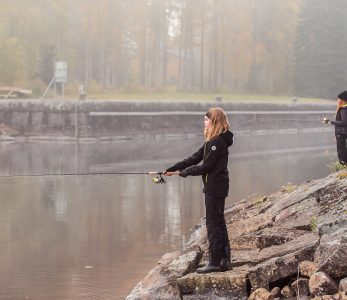 Työttö kalastaa joen rannalla.