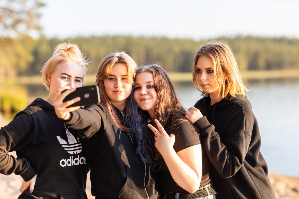 Leirikoululaisia ottamassa selfietä rannalla.