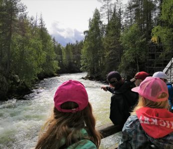 Lapsia katsomassa sillalla, kuinka koskessa virtaa paljon vettä.