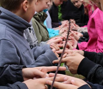 Iso joukko lapsi kannattelee mato-onkea sormenpäillään.