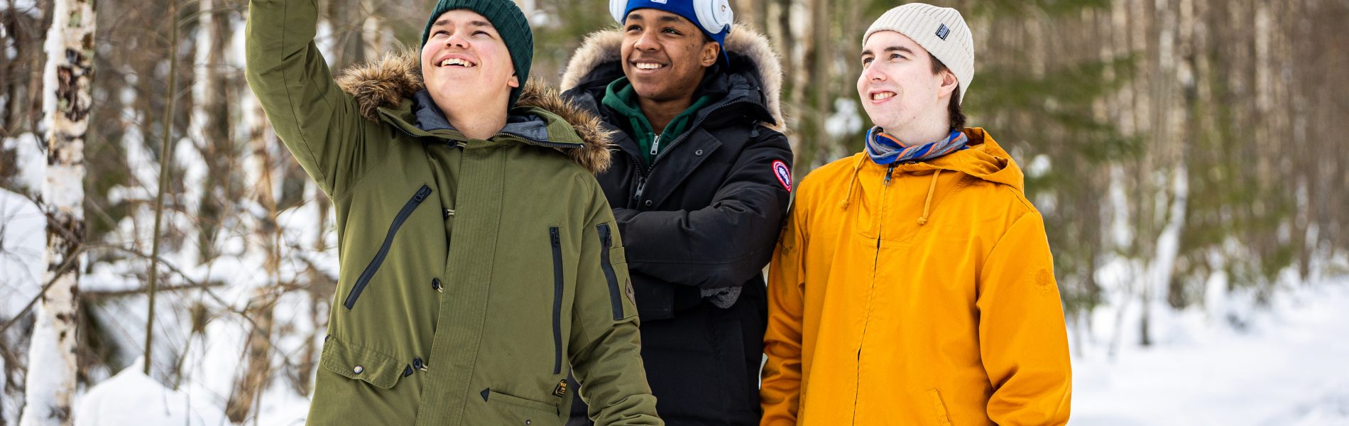 Kolme nuorta ottamassa selfietä lumisessa metsässä.