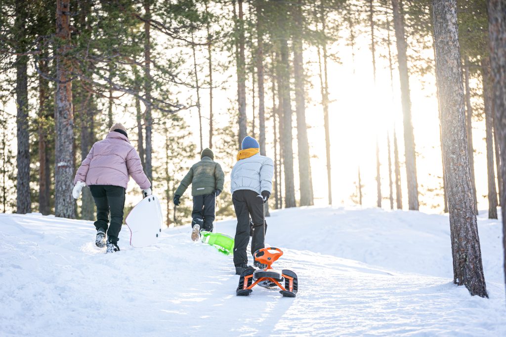 Lapsia kiipeämässä pulkkamäen laelle.