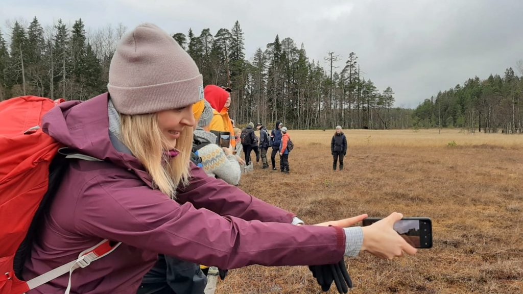 Johanna Sutinen ottamassa selfietä suon läpi kulkevilla pitkospuilla.