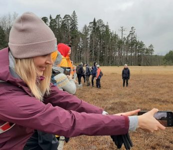 Johanna Sutinen ottamassa selfietä suon läpi kulkevilla pitkospuilla.