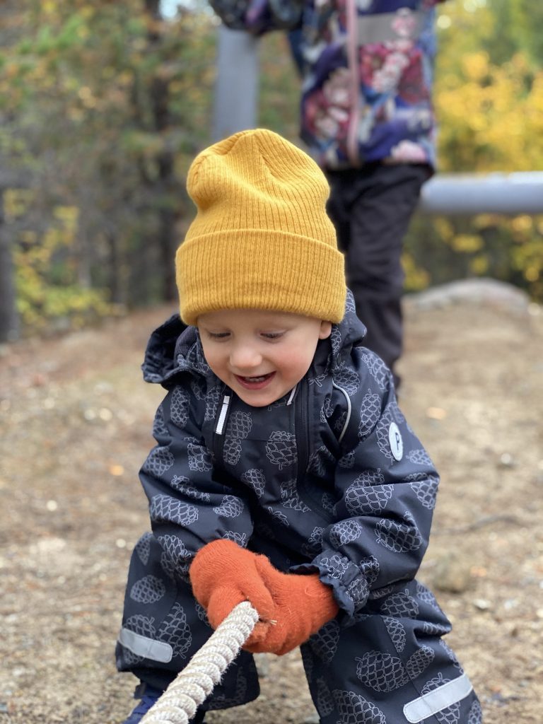 Lapsi kiipeilee iloisena alaköysiradalla.