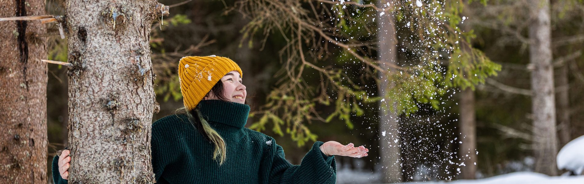 Nainen heittää lunta ilmaan puun takaa - Lasten ja nuorten joulurauhan julistus.