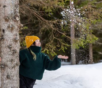 Nainen heittää lunta ilmaan puun takaa - Lasten ja nuorten joulurauhan julistus.