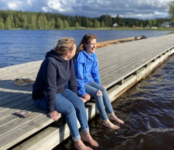 Kaksi henkilöä laiturilla Pielisen rannalla.