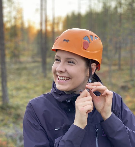 Nainen kiinnittää kypärää metsässä.