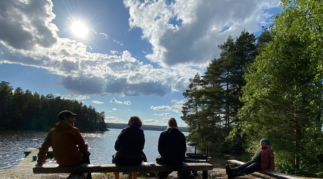 Neljä silhuettihahmoa kalliosaarella.