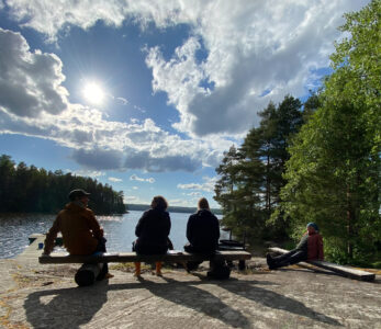Neljä silhuettihahmoa kalliosaarella.